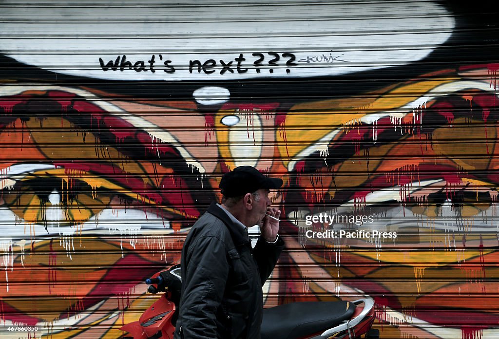 A man walks in front of a graffiti, in central Athens.