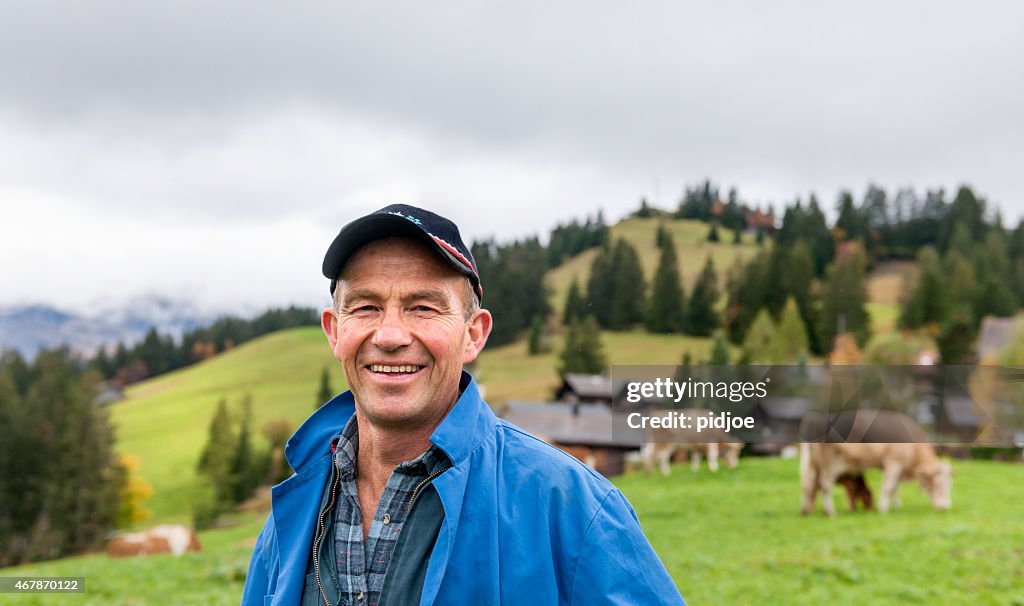 Portrait Of Dairy Farmer In Field With Cattle