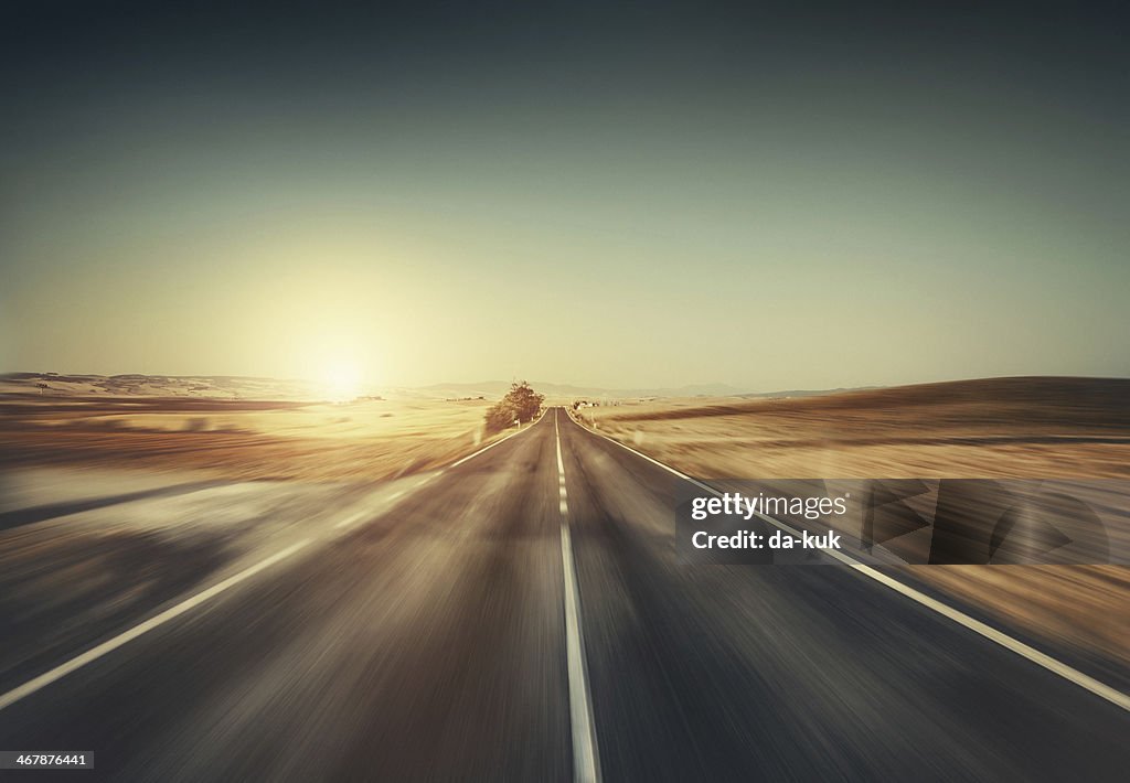 Forma de avanzar en movimiento.  Vacía carretera al atardecer.