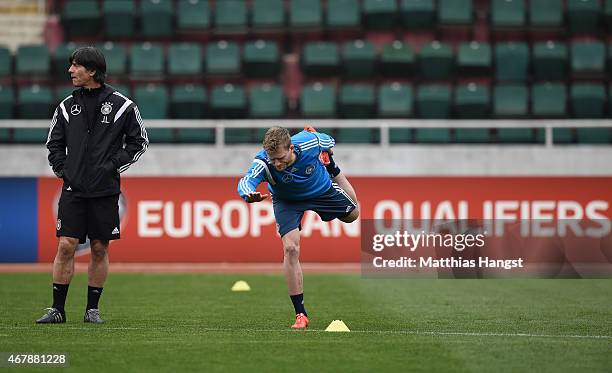 Head coach Joachim Loew of Germany observes the stretching session of Andre Schuerrle of Germany during a Germany training session ahead of their...