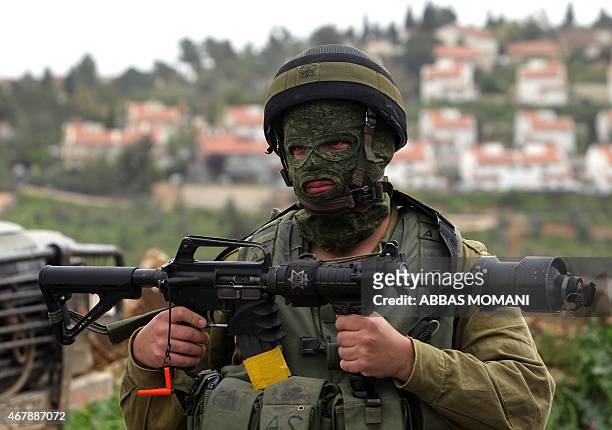 An Israeli soldier stand holding his weapon during clashes with Palestinian protesters following a demonstration against Palestinian land...
