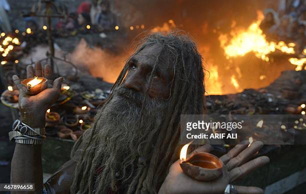 Pakistani devotee carries light lamp as he stand infront of fire at the shrine of Sufi saint Hazrat Shah Hussain, popularly known as Madhu Lal...