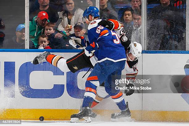 Johnny Boychuk of the New York Islanders and Rickard Rakell of the Anaheim Ducks battle for the puck along the boards at Nassau Veterans Memorial...