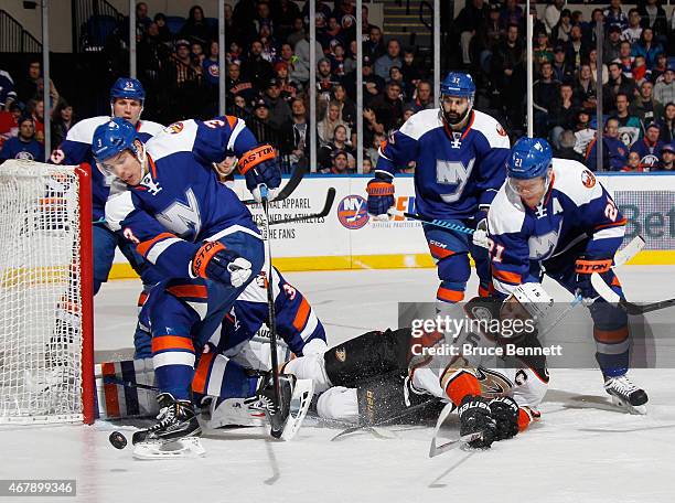 Travis Hamonic and Kyle Okposo of the New York Islanders defend against Ryan Getzlaf of the Anaheim Ducks during the first period at the Nassau...