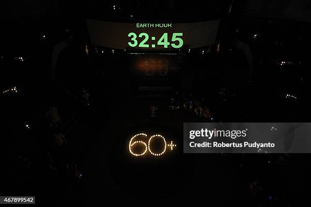 Burning candles displayed in the shape of 60+ during Earth Hour celebration at Sheraton Hotel on March 28, 2015 in Surabaya, Indonesia. Millions of...