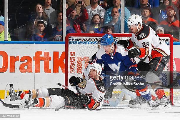 Clayton Stoner of the Anaheim Ducks falls to the ice as Anders Lee of the New York Islanders is checked by Simon Despres of the Anaheim Ducks at...