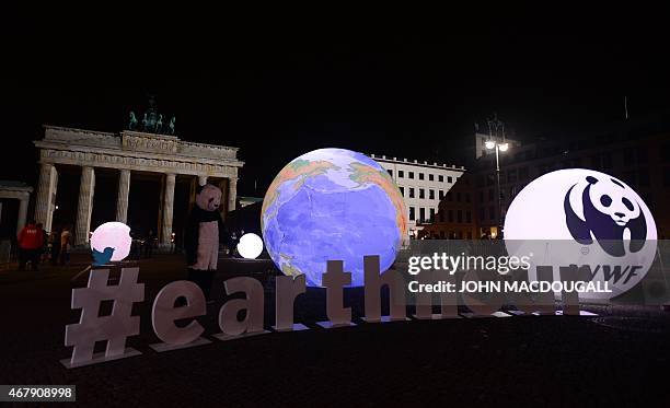 Activist dressed as a panda bear stands next to an illuminated globe in front of the Brandenburger Gate in Berlin during the the global climate...