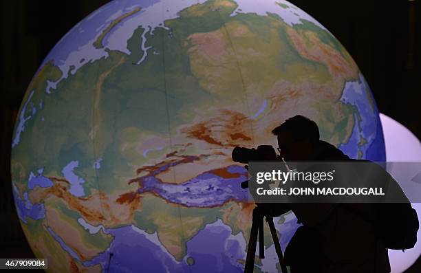 Photographer is silhouetted against an illuminated globe at the Brandenburger Gate in Berlin ahead of the the global climate change awareness...