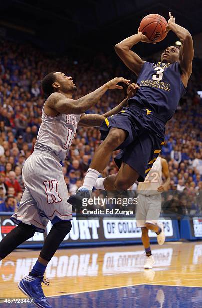 Juwan Staten of the West Virginia Mountaineers drives to the basket and shoots against Naadir Tharpe of the Kansas Jayhawks in the second half at...
