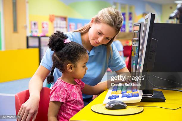 little girl at nusery learning new technology with teacher. - baby room stock pictures, royalty-free photos & images