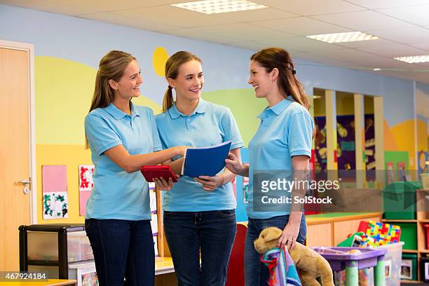 three teachers in a nursery classroom in discussion - preschool stock pictures, royalty-free photos & images