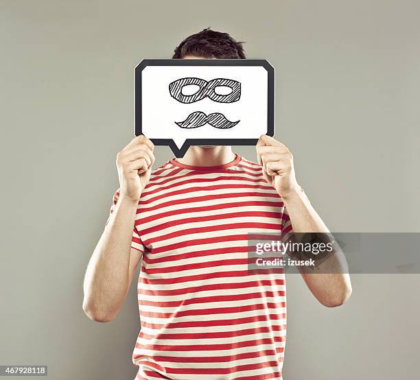 young man holding speech bubble with mustache and mask - disguise stock pictures, royalty-free photos & images