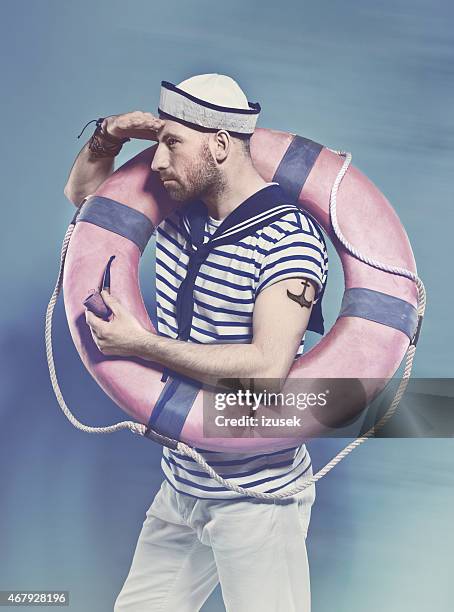 bearded man in sailor style outfit holding lifebuoy - sailor suit stock pictures, royalty-free photos & images