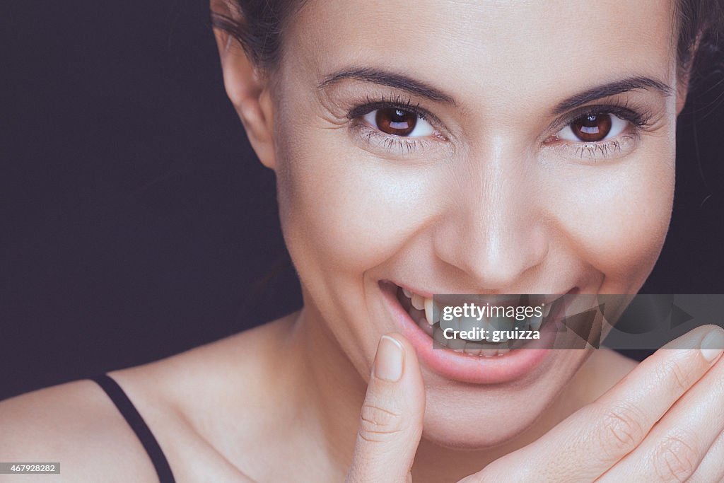 Beautiful young smiling woman covering her smile with hand