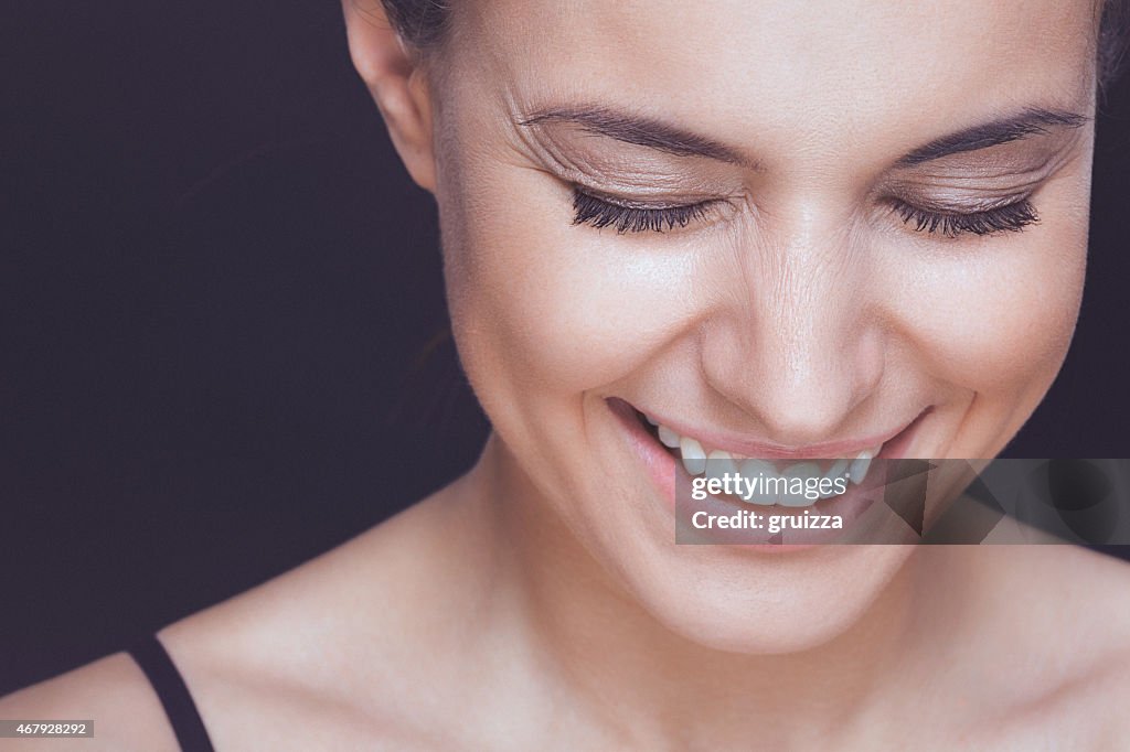 Beautiful young smiling woman with visible wrinkles around her eyes