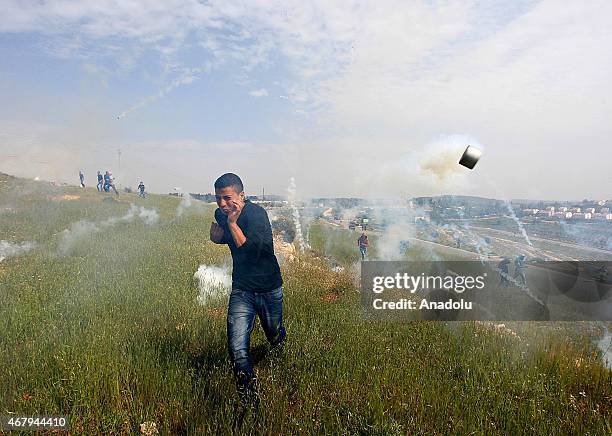 Palestinian protester run to cover from gas canisters fired by Israeli securitty during clashes following a demonstration against Jewish settlement...