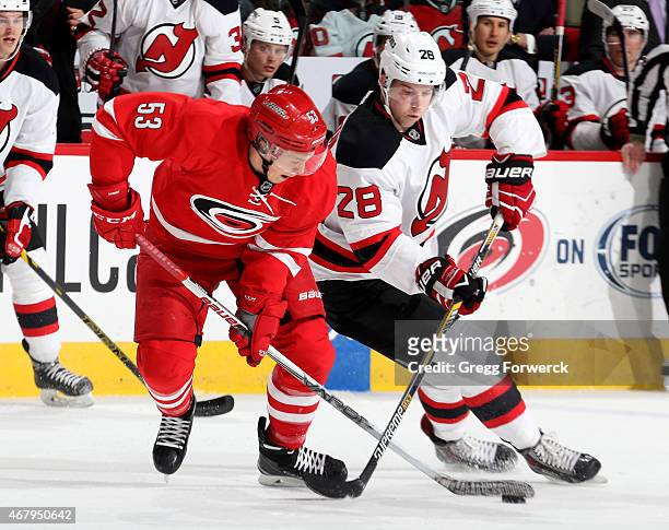 Jeff Skinner of the Carolina Hurricanes and Damon Severson of the New Jersey Devils battle for the puck during their NHL game at PNC Arena on March...