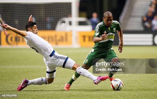 Darlington Nagbe of the Portland Timbers avoids the tackle of Matias Laba of the Vancouver Whitecaps FC in MLS action on March 2015 at BC Place...