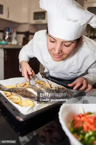 weibliche küchenchef bereitet fisch in der küche - chef smelling food stock-fotos und bilder