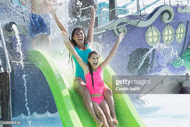 mother and daughter going down water slide - water park stock pictures, royalty-free photos & images