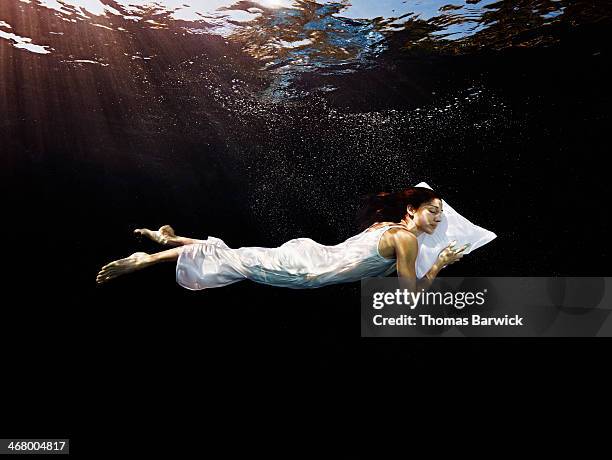 woman with head on pillow sleeping underwater - nightdress stock-fotos und bilder