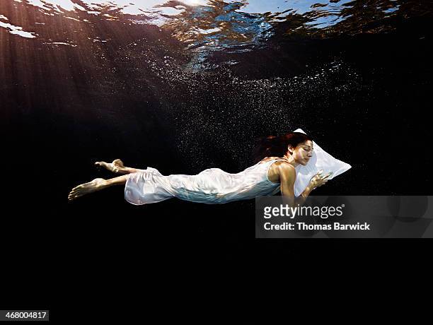 woman with head on pillow sleeping underwater - dreamlike stock pictures, royalty-free photos & images