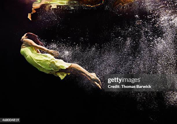 woman in yellow dress swimming to water surface - break through fotografías e imágenes de stock