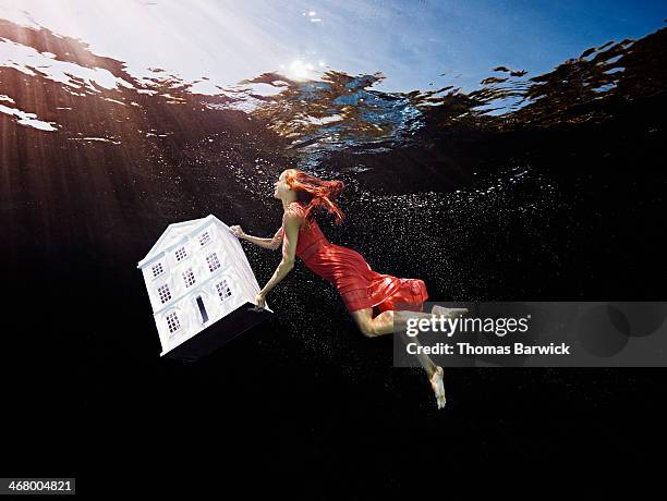 view from underwater of woman lifting house - underwater female models stock pictures, royalty-free photos & images