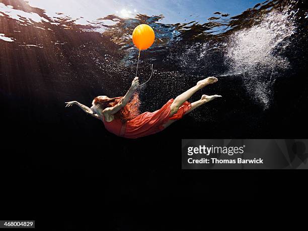 view from underwater of woman holding balloon - dreamlike stock pictures, royalty-free photos & images