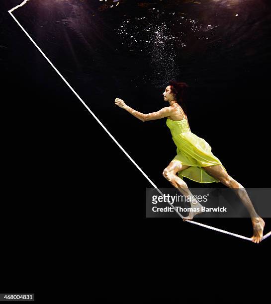 view from underwater of woman walking up tightrope - robe jaune photos et images de collection