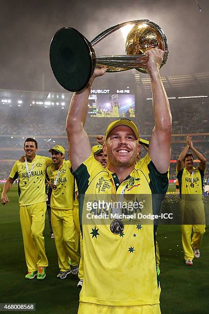 David Warner of Australia holds the trophy up as he celebrates winning during the 2015 ICC Cricket World Cup final match between Australia and New...