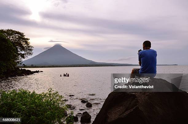 man sitting on a rock watching a volcano at sunset - santa cruz de la sierra bolivia fotografías e imágenes de stock