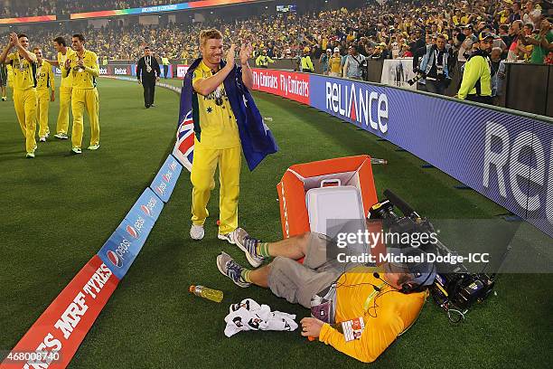 David Warner of Australia celebrates winning as a cameraman falls in front of him during the 2015 ICC Cricket World Cup final match between Australia...