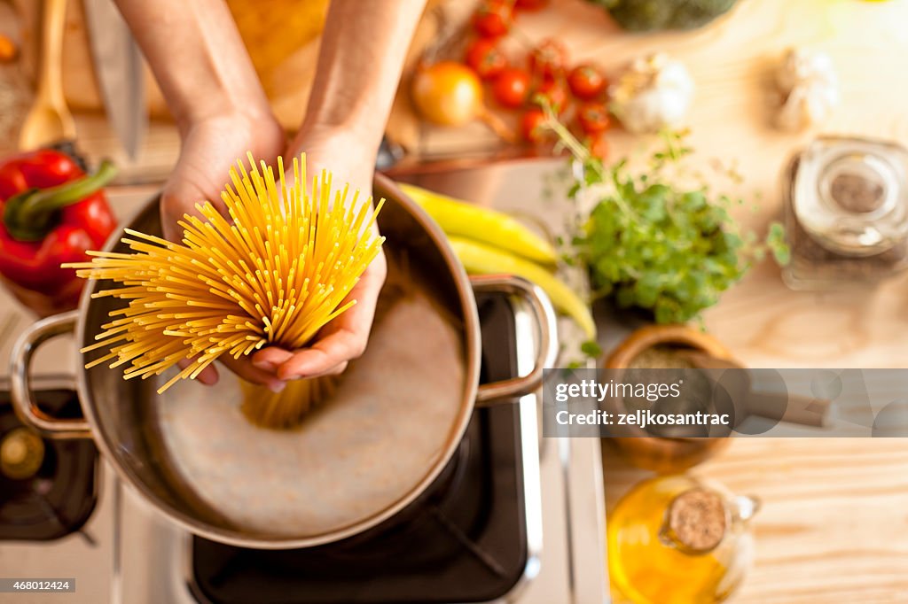 Woman in the kitchen holding spaghetti
