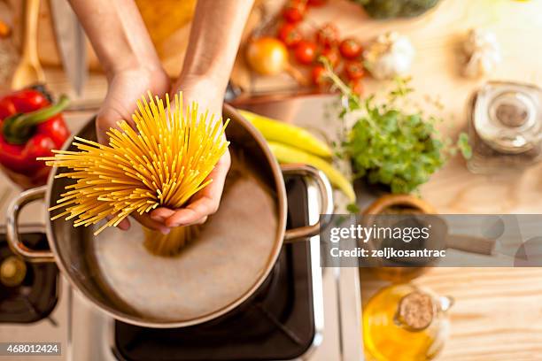 woman in the kitchen holding spaghetti - spaghetti stockfoto's en -beelden