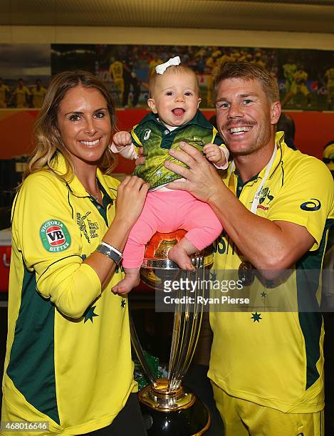 David Warner of Australia, his fiance Candice Falzon and their daughter Ivy Warner pose with the trophy in the changerooms during the 2015 ICC...