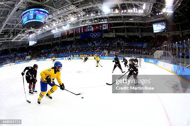 Maria Lindh of Sweden skates with the puck against Moeko Fujimoto and Haruna Yoneyama of Japan during the Women's Ice Hockey Preliminary Round Group...