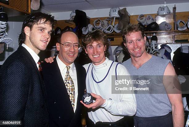 Wayne Gretzky of the Los Angeles Kings poses in the locker room with Luc Robitaille, TV commentator Bob Miller, Marty McSorley and the puck he scored...