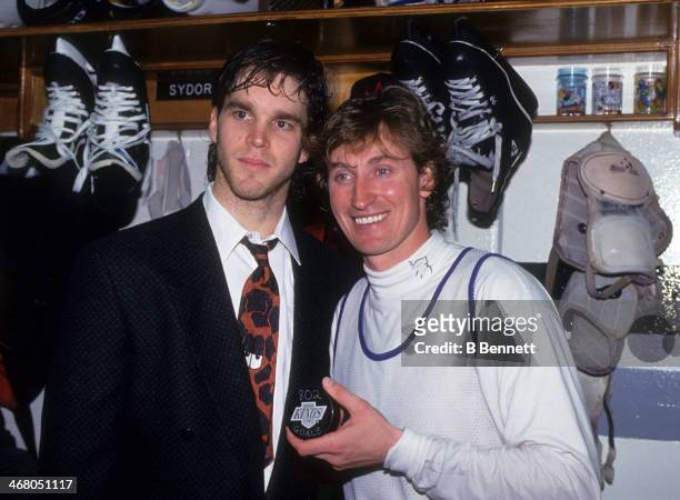 Wayne Gretzky of the Los Angeles Kings poses with his teammate Luc Robitaille and the puck he scored his 802nd career goal with after the game...