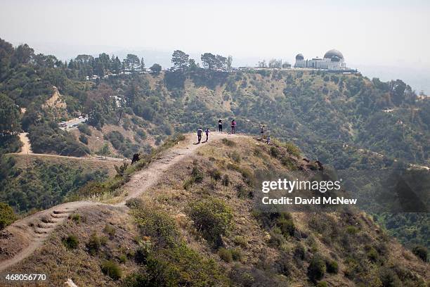 People hike along a ridge overlooking the Griffith Observatory where vegetation is quickly drying out in Griffith Park on March 29, 2015 in Los...