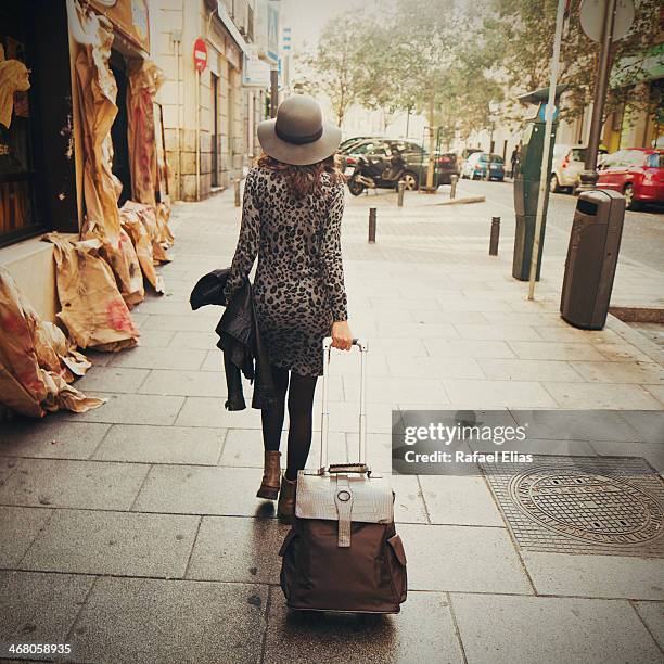 woman walking with luggage - gepardenfell stock-fotos und bilder