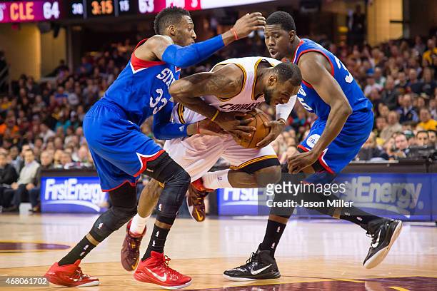 Robert Covington and Henry Sims of the Philadelphia 76ers try to stop LeBron James of the Cleveland Cavaliers during the second half at Quicken Loans...