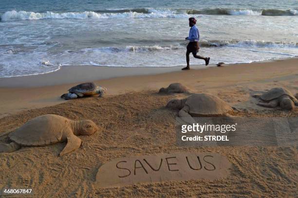 The carcass of a dead olive ridley turtle is pictured amid a sand sculpture of sea turtles by sand artist Sudarsan Pattnaik at Puri beach, some 65...