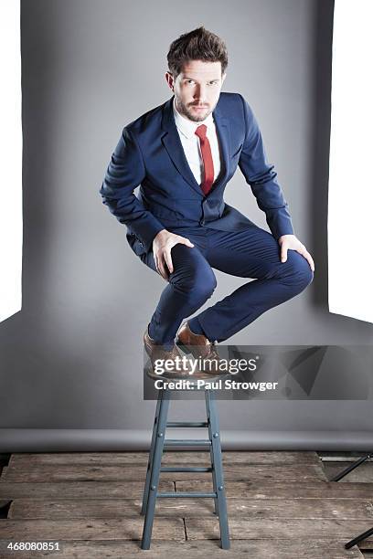 self, blue suit on stool. - hand op knie stockfoto's en -beelden