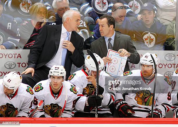 Head Coach Joel Quenneville and Assistant Coach Kevin Dineen of the Chicago Blackhawks discuss strategy at the bench during third period action...