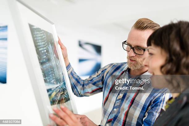 artist showing gallery owner his work - man stand stockfoto's en -beelden