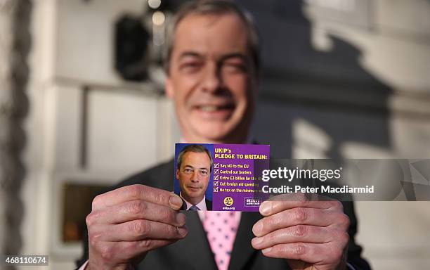 United Kingdom Independence Party leader Nigel Farage holds up a pledge card as he arrives in Westminster on March 30, 2015 in London, England....