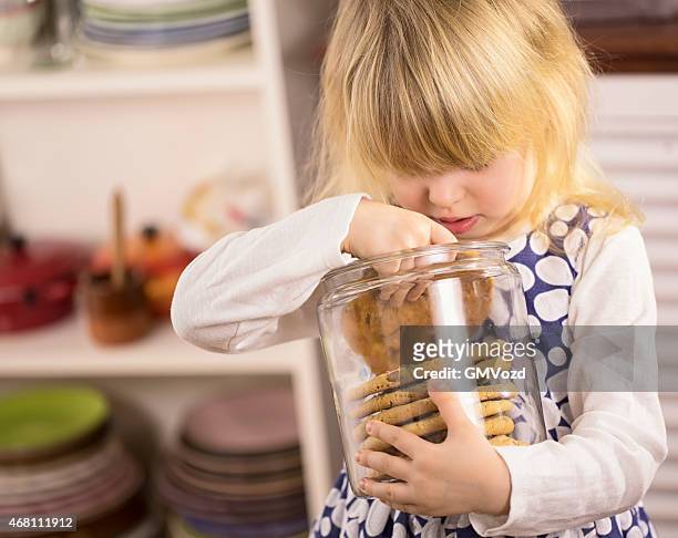 little girl holding chocolate chip cookie in a jar - cookie jar stock pictures, royalty-free photos & images