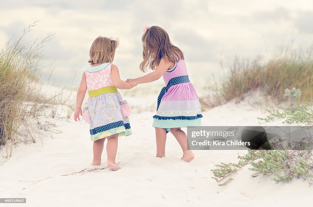 Sisters holding hands in the sand dunes