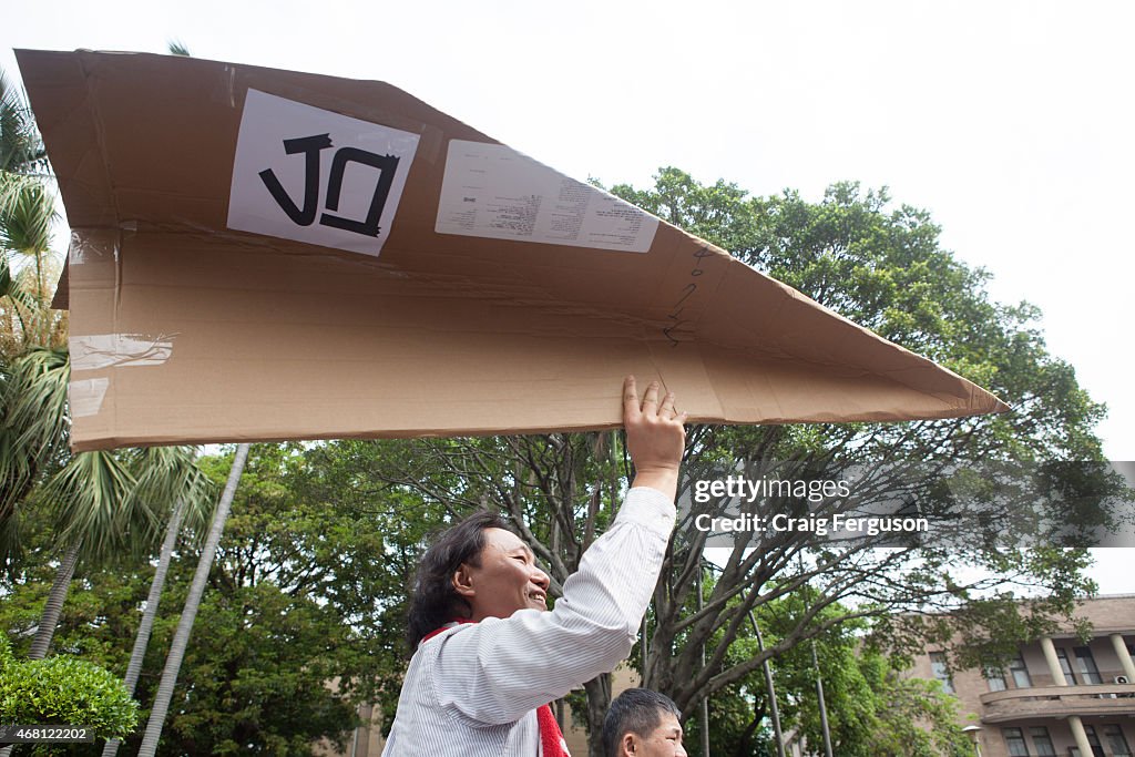 A man holds a giant carboard plane during a protest against...